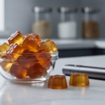 Close-up of hemp-derived THC gummies in a glass bowl next to an unbranded vape device on a clean countertop.